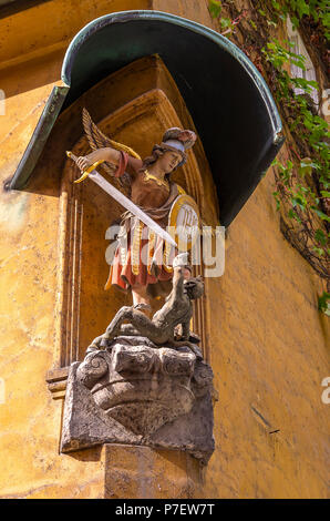 Fuggerei, Augsburg, Bayern, Deutschland - Darstellung des Erzengels Michael im Kampf gegen die Teufel an der Ecke eines Hauses. Stockfoto