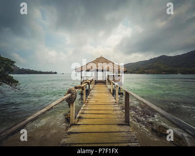 Hölzerne Seebrücke mit einer überdachten Hütte am Ozean Küste an einem bewölkten Tag Stockfoto