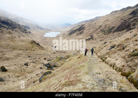 Zwei Wanderer gehen hinunter in ein Tal Trail von einem Munro in den schottischen Highlands, Knoydart Halbinsel im Nordwesten von Schottland, Großbritannien. Stockfoto