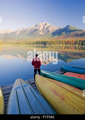Einsame mittleren Alter Mann stehend auf Dock mit Kanus bei Pyramid Mountain im Pyramid Lake, Jasper National Park, Alberta, Kanada. Stockfoto