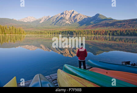 Einsame mittleren Alter Mann stehend auf Dock mit Kanus bei Pyramid Mountain im Pyramid Lake, Jasper National Park, Alberta, Kanada. Stockfoto