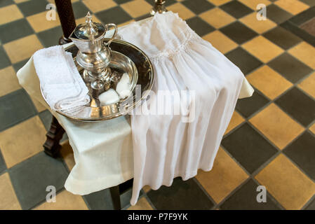 Silber Fach und Kanne mit Wasser Zubehör und ein Kleid für die Taufe des Kindes im Einklang mit dem kirchlichen Traditionen Stockfoto