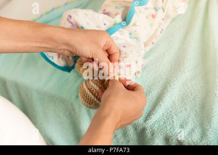 Junge Mutter Dressing ihr neugeborenes Baby Boy nach dem Windelwechsel Stockfoto