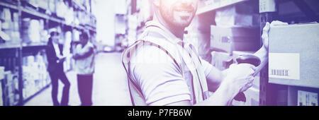 Lager Arbeiter Scan-Feld während lächelnd in die Kamera Stockfoto