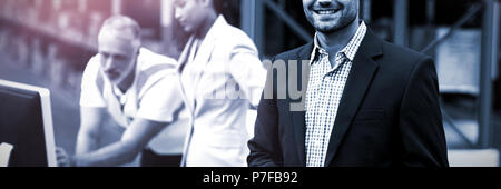 Fokus auf Manager lächelt und hält eine Tablette vor seinen Kollegen Stockfoto