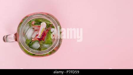 Glas kalte frische Limonade mit Stück Wassermelone und Eis auf rosa Hintergrund Stockfoto