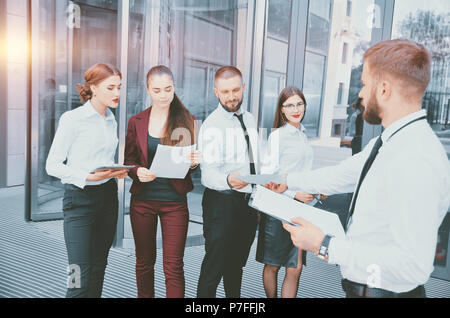 Treffen. Teamarbeit. Der Chef die Gespraeche mit der Office Personal vor dem Hintergrund eines mehrstöckigen Büro. Ein Team junger Mitarbeiter in einem d eingerückt Stockfoto