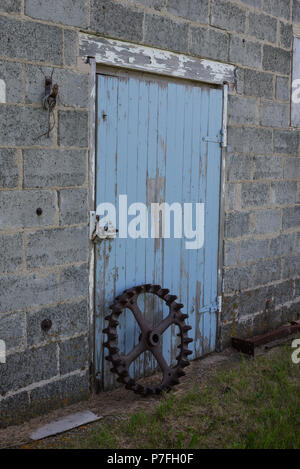 Vintage Stahl packer Rad vor einem blauen antike Scheunentor außerhalb von Swift Current, Saskatchewan, Kanada Stockfoto