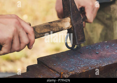 Schmied geschmiedete Eisen traditionelle Hammer schlagen. Schmiedehammer von Metallkonstruktionen im Freien in der Natur. Stockfoto