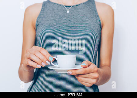 Die Frau Hände mit trendigen Maniküre kleine Espresso Tasse und Untertasse, close-up. Zugeschnittenes Bild Frau mit Kaffee. Stockfoto