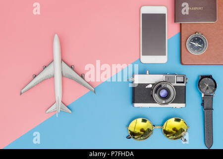 Spielzeug Flugzeug mit travel Objekte auf dem auf Blau und Rosa pastell Hintergrund Stockfoto