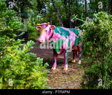 Berlin-Dahlem. Rosa und grün Kuh Statue mit Bell Peers durch Büsche in den Garten Stockfoto