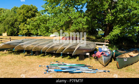 Pataholm, Schweden - 28. Juni 2018: Alltag und Ort. Reihe von Vermietung Kanus mit Paddel und Schwimmwesten am Ufer. Stockfoto