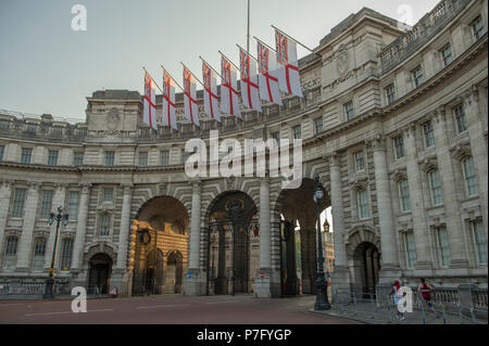 Admiralty Arch London, UK. 6. Juli, 2018. Nach einem drückend und feuchte Nacht, London aufwacht an, um mehr heiße Wetter mit wolkenlosem Himmel und kein Wind. White Ensign Flags sind vom Admiralty Arch am östlichen Ende der Mall drapiert, durch die frühe Morgensonne beleuchtet. Credit: Malcolm Park/Alamy Leben Nachrichten. Stockfoto