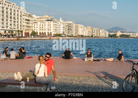 Menschen entspannend auf Thessaloniki Waterfront mit Apartment Blocks auf Nikis Avenue und den Weißen Turm im Hintergrund, Mazedonien, Nordgriechenland Stockfoto