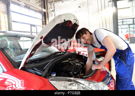 Mechaniker arbeitet an den Motor eines Fahrzeugs in der Werkstatt - Wartung und Kundendienst Stockfoto