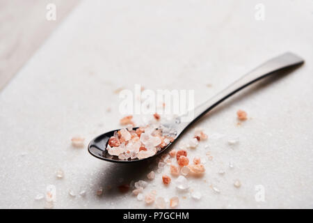 Schwarz Löffel, rosa Himalaya-salz auf Marmor tisch mit kopieren. Close Up. Stockfoto