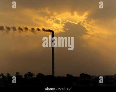 Sonnenuntergang am Nil Ägypten im industriellen Bereich mit Verschmutzung von rauchenden Schornstein Erhöhung der dramatischen orange Farben in den Wolken Stockfoto