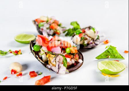 Peruanische Küche Jakobsmuscheln à la chalaca. Jakobsmuscheln mit Zwiebeln, Tomaten, Mais, Koriander und Zitrone. Stockfoto