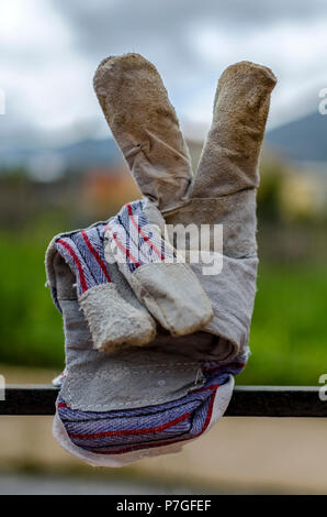 Worker's Handschuh mit den Sieg Zeichen (V) auf die natürlichen Hintergrund isoliert Stockfoto