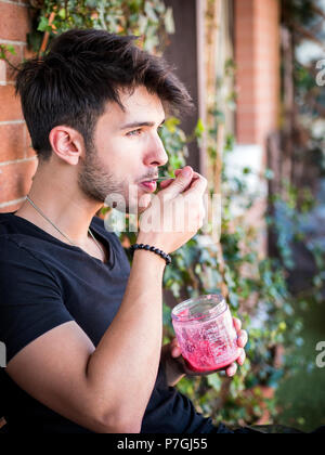 Junger Mann Eis essen auf der Terrasse Stockfoto