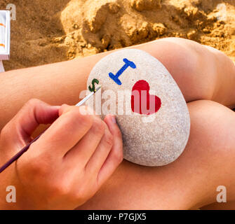 Frau hand mit Pinsel Zeichnung auf Kiesel - ich Herz, s. Stockfoto