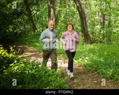Älteres Paar tragen Sportswear und läuft im grünen Wald bei mountainduring Feder Stockfoto