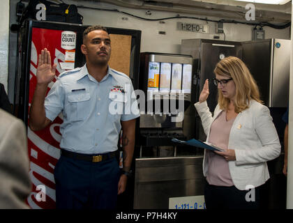 Seaman Kenwyn Berkeley, Crewmitglied an Bord Coast Guard Cutter entschlossen, eine 210-Fuß-medium - Ausdauer Vertrauen Class Cutter in St. Petersburg, Florida homeported, nimmt den Eid der Treue Freitag, 29. Juni 2018 an Bord der Cutter ein Bürger während einer U.S. Citizenship und Immigration Services Einbürgerung Zeremonie zu werden. Berkeley erforderlich war Teil einer Reihe von Tests und Interviews von der U.S. Citizenship und Immigration Services als Teil der Einbürgerung verabreicht. (U.S. Coast Guard Foto von Petty Officer 1st Class Michael De Nyse) Stockfoto