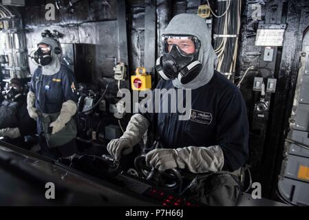 180630-N-DZ 642-0178 MITTELMEER (30. Juni 2018) Quartermaster 1. Klasse Josua Geoghegan mans das Ruder während eines simulierten chemischen, biologischen, radiologischen und nuklearen Waffe General Quarters Training an Bord der geführte-missile Cruiser USS Normandie (CG60). Die Normandie ist derzeit als Teil der Harry S. Truman Carrier Strike Group bereitgestellt. Mit Harry S. Truman als Flaggschiff, Bereitstellung Streik Vermögenswerte des Konzerns gehören Personal, Schiffe und Flugzeuge von Carrier Strike Group (CSG) 8, Destroyer Squadron (DESRON) 28 und Carrier Air Wing (Cvw) 1; sowie die deutsche Fregatte Sachsen-Klasse FG Stockfoto