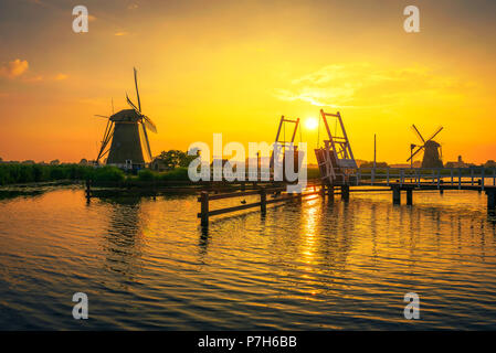 Schönen Sonnenuntergang über eine historische hölzerne Zugbrücke und alten Windmühlen von Kinderdijk, Niederlande. Dieses System der 19 Windmühlen wurde um 1740 ein gebaut Stockfoto