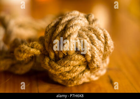 Kotflügel-marine Knoten der dicke braune Seil auf einer hölzernen Hintergrund, Nahaufnahme Stockfoto