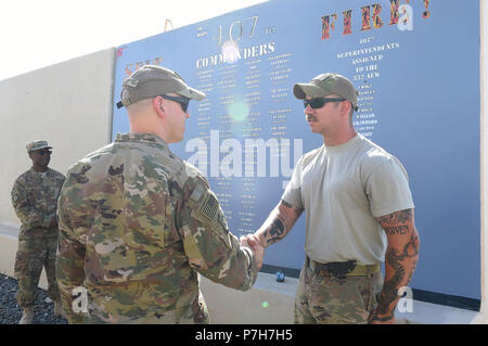 Oberst Scott Gibson, 407 Air Expeditionary Gruppenkommandant, Münzen Älterer Flieger Adam Huckabee, 407 Expeditionary Logistik Bereitschaft Squadron Feuer und tanken Lkw-Betreuer, für eine gut vor einem frisch lackiert t-wall vor der 407 AEG-Stammwerk Gebäude an einem geheimen Ort im Südwesten Asien Juli 2, 2018. Die Wand listet die Namen aller 42 407 Kommandeure. Es hat auch die Namen der Gruppe Betriebsleiter ab 2015, wenn der 407 AEG unter die 332 Air Expeditionary Wing ausgerichtet. (U.S. Air Force Foto: Staff Sgt. Dana J. Kabel) Stockfoto