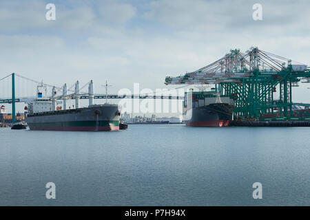 Kopf auf Der Bulk Carrier, La Bamba, begleitet von Schleppern und verlassen den Hafen von Los Angeles, Kalifornien. Der Vincent Thomas Bridge hinter sich. Stockfoto