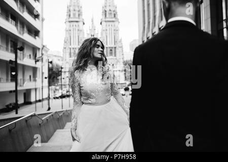 Stilvolle braut und bärtigen Bräutigam am Hochzeitstag posieren. Schöne glücklich verheiratetes Paar auf den Straßen der Stadt. Stockfoto