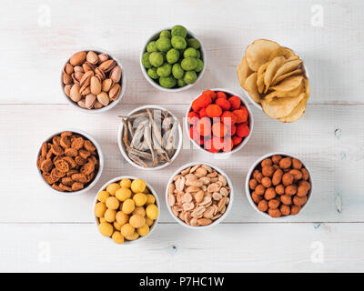 Sortiment von verschiedenen Snack für Bier, Wein, Party. Erdnüsse in Coconut Glasur, grüne vasabi, rote scharfe Chili, gelben Käse Glasur, Chips, Pistazie, Stockfoto