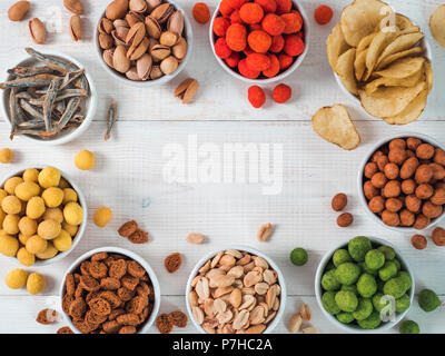 Sortiment von verschiedenen Snack für Bier, Wein, Party. Erdnüsse in Coconut Glasur, grüne vasabi, rote scharfe Chili, gelben Käse Glasur, Chips, Pistazie, Stockfoto