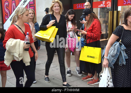 Käufer und Touristen die Einkaufstaschen zu Fuß vorbei am Kaufhaus Selfridges in der Oxford Street in Central London. Stockfoto