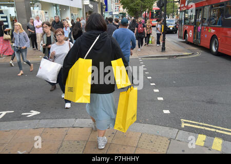 Käufer und Touristen die Einkaufstaschen zu Fuß vorbei am Kaufhaus Selfridges in der Oxford Street in Central London. Stockfoto