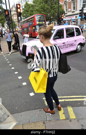 Käufer und Touristen die Einkaufstaschen zu Fuß vorbei am Kaufhaus Selfridges in der Oxford Street in Central London. Stockfoto