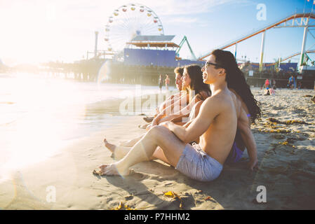 Gruppe von Freunden am Strand sitzen Stockfoto