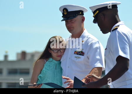 AOC Christopher Crabtree, von der USS Gerald R. Ford (CVN-78), erhält eine warme Umarmung von einem Familienmitglied während seiner Dienstzeit re-Zeremonie auf der USS Wisconsin. Die USS Wisconsin (BB-64) ist ein Iowa - Klasse Schlachtschiff, die ursprünglich im Jahr 1944 in Betrieb genommen. Da stillgelegt wird, hat neben dem Hampton Roads Naval Museum und Nauticus liegt in der Innenstadt von Norfolk, Virginia als Museumsschiff. Das Museum ist in der Lage, militärische Zeremonien, wie Re-enlistments, Promotions und Abgänge an Bord der legendären USS Wisconsin kostenlos. Interessierte Befehle und Personen sollten Stockfoto