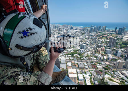 180702-N-CW 570-1655 HONOLULU, Hawaii (2. Juli 2018) Mass Communication Specialist 2. Klasse Travis Litke, Commander, U.S. dritte Flotte zugeordnet, schießt Bilder von einem MH-60S Sea Hawk Hubschrauber, Hubschrauber Meer Combat Squadron 8 zugewiesen, während der Rand des Pazifik (Rimpac) 2018 Übung, Juli 2. 25 Nationen, 46 Schiffe, 5 U-Boote, über 200 Flugzeuge und 25.000 Angestellte beteiligen sich an Rimpac vom 27. Juni bis 2. August in und um die hawaiischen Inseln und Südkalifornien. Die weltweit größte internationale maritime Übung RIMPAC bietet eine einzigartige Ausbildung Stockfoto