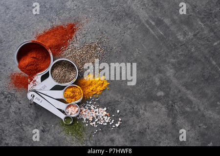 Flach der verschiedenen Gewürze im Messbecher auf Tisch aus Stein. Ansicht von oben mit der Kopie. Stockfoto