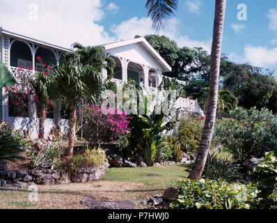 Palmen und exotische Sträucher im Garten vor der traditionellen Haus in Westindien Stockfoto