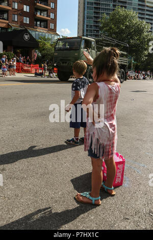 Kinder wave am Ohio National Guard Soldaten Fahren einer Light Medium Tactical Vehicle (LMTV) durch die Straßen der Innenstadt von Columbus, Ohio während der Rot Weiß und Boom Parade, 3. Juli 2018. Mehr als 100.000 Zuschauer säumten die 1 Meile parade Route zum Tag der Unabhängigkeit zu feiern und zu sehen, Und danke, Militärdienst Mitglieder und Veteranen. Ohio National Guard Unterstützung für die Parade enthalten auch eine gemeinsame Color Guard und die 122 Army Band. (Ohio National Guard Foto von Sgt. Joanna Bradshaw) Stockfoto