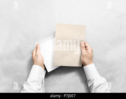 Hand mit leeren Umschlag und Kraft schreiben Mockup, isoliert. Arm halten Sie clear Broschüre Vorlage mock up. Grußkarte Broschüre Oberflächengestaltung. Einladung drucken Anzeigen. Lesen schreiben Umschlag. Stockfoto