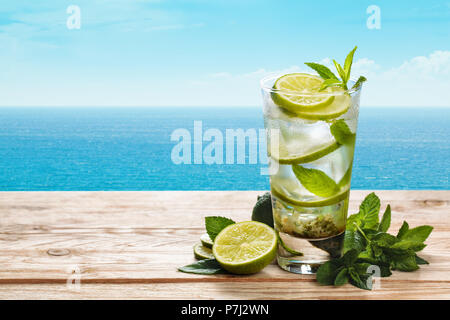 Frischen mojito Cocktail auf Blau rustikal Tisch mit blauen Meer im Hintergrund. Stockfoto