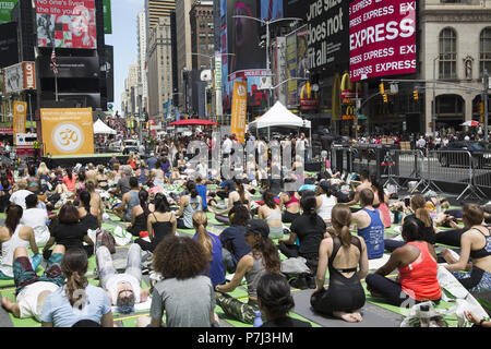 Yoga Enthusiasten nehmen kostenlose Kurse in den jährlichen Times Square Sommersonnenwende Feier mit Klassen den ganzen Tag inmitten der Material glitz der Nachbarschaft, New York City. Stockfoto