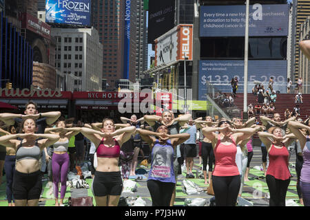 Yoga Enthusiasten nehmen kostenlose Kurse in den jährlichen Times Square Sommersonnenwende Feier mit Klassen den ganzen Tag inmitten der Material glitz der Nachbarschaft, New York City. Stockfoto