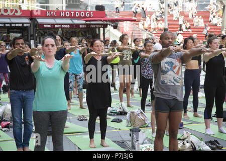 Yoga Enthusiasten nehmen kostenlose Kurse in den jährlichen Times Square Sommersonnenwende Feier mit Klassen den ganzen Tag inmitten der Material glitz der Nachbarschaft, New York City. Stockfoto